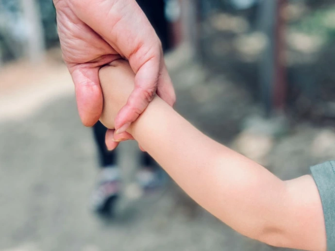 person in gray long sleeve shirt holding babys hand